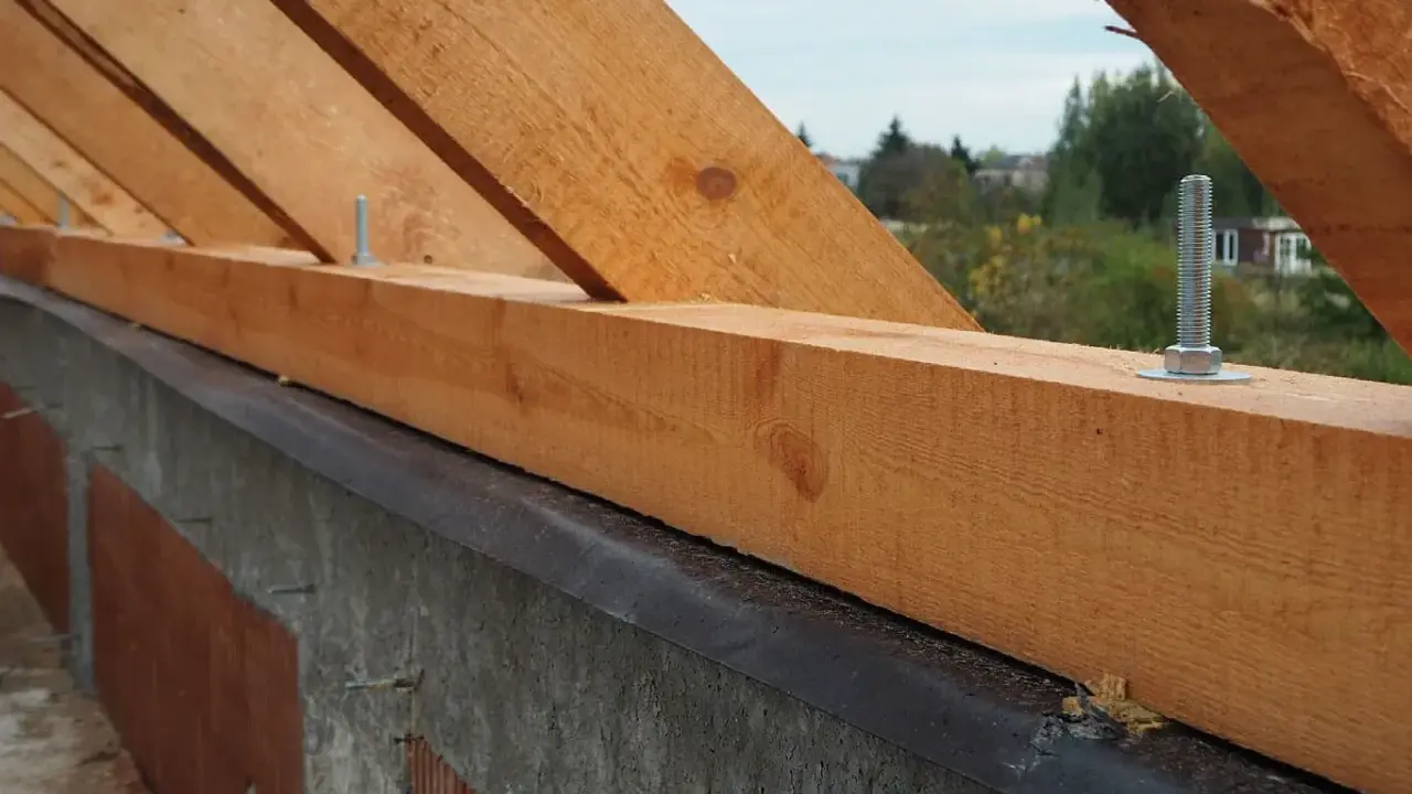 Murłata, drewniana belka na ścianie, stanowi podstawę więźby dachowej. Widać śruby mocujące ją do konstrukcji.