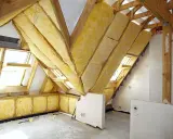 Trwa adaptacja poddasza. Widoczne drewniane konstrukcje, wełna mineralna jako izolacja i okna dachowe.