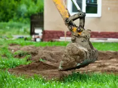 Łyżka koparki wykonuje niwelację terenu, przygotowując go pod budowę.