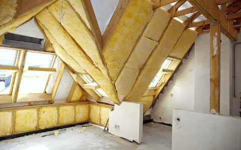 Trwa adaptacja poddasza. Widoczne drewniane konstrukcje, wełna mineralna jako izolacja i okna dachowe.
