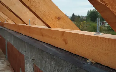Murłata, drewniana belka na ścianie, stanowi podstawę więźby dachowej. Widać śruby mocujące ją do konstrukcji.