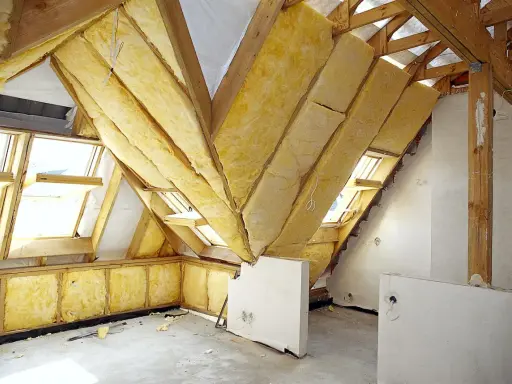 Trwa adaptacja poddasza. Widoczne drewniane konstrukcje, wełna mineralna jako izolacja i okna dachowe.