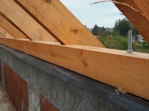 Murłata, drewniana belka na ścianie, stanowi podstawę więźby dachowej. Widać śruby mocujące ją do konstrukcji.