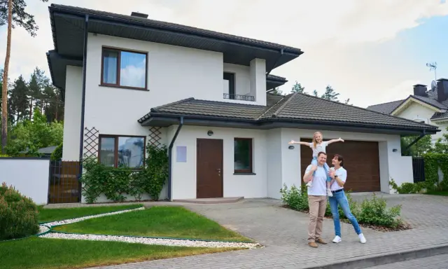 Rodzina przed nowoczesnym domem. Zastanawiasz się, ile realnie kosztuje budowa domu?