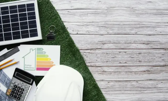 Planujesz audyt energetyczny? Sprawdź, ile kosztuje i jak poprawić efektywność energetyczną domu. Na zdjęciu panele słoneczne, kalkulator i certyfikat.